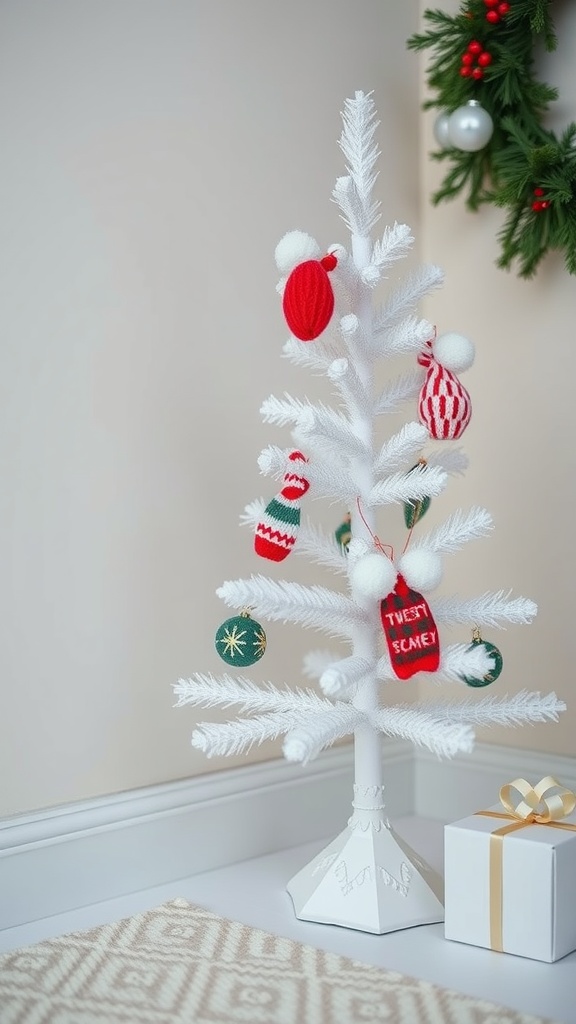 A mini white Christmas tree decorated with cozy knit ornaments and a gift box.